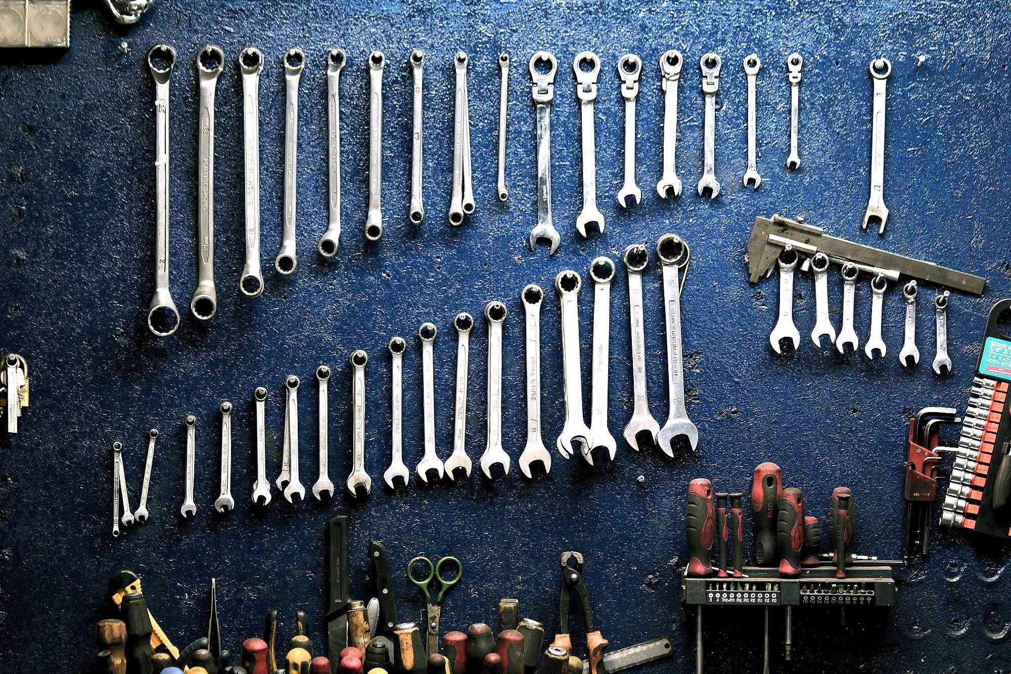 Wrenches, rulers, screwdrivers and other tools are arrayed on a pegboard